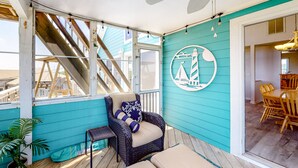 A covered outdoor area with a wicker chair, a small table, and a potted plant. - Amazing dog-friendly home with private pool, game room, AC, & W/D - near beach (Salvo)