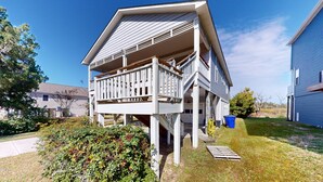 Een tweelaags huis met een balkon, een klein terras en een gazon.