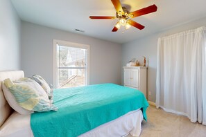 A bedroom with a bed, a ceiling fan, a window, and a cabinet. - Marsh-View Escape: Walk to Beach | Marsh-View Escape with Screened Porch & Outdoor Shower (Oak Island)