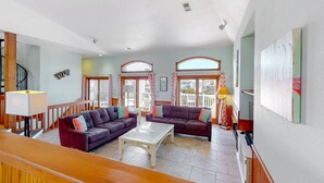 A spacious living area with two sofas, a coffee table, and a staircase. - Outer Banks house with private pool, hot tub, W/D & ocean view - dog-friendly (Avon)