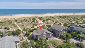 Ett flygbildsbild av ett bostadsområde med hus, en strand och en röd markering som visar en fastighet till salu via mäklarfirman Hattenas Realty.