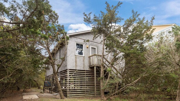 Eine rustikale Holzhütte mit einer Holzterrasse, umgeben von Bäumen.