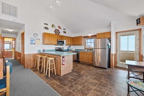 A modern kitchen with wooden cabinets, stainless steel appliances, and a central island with stools.