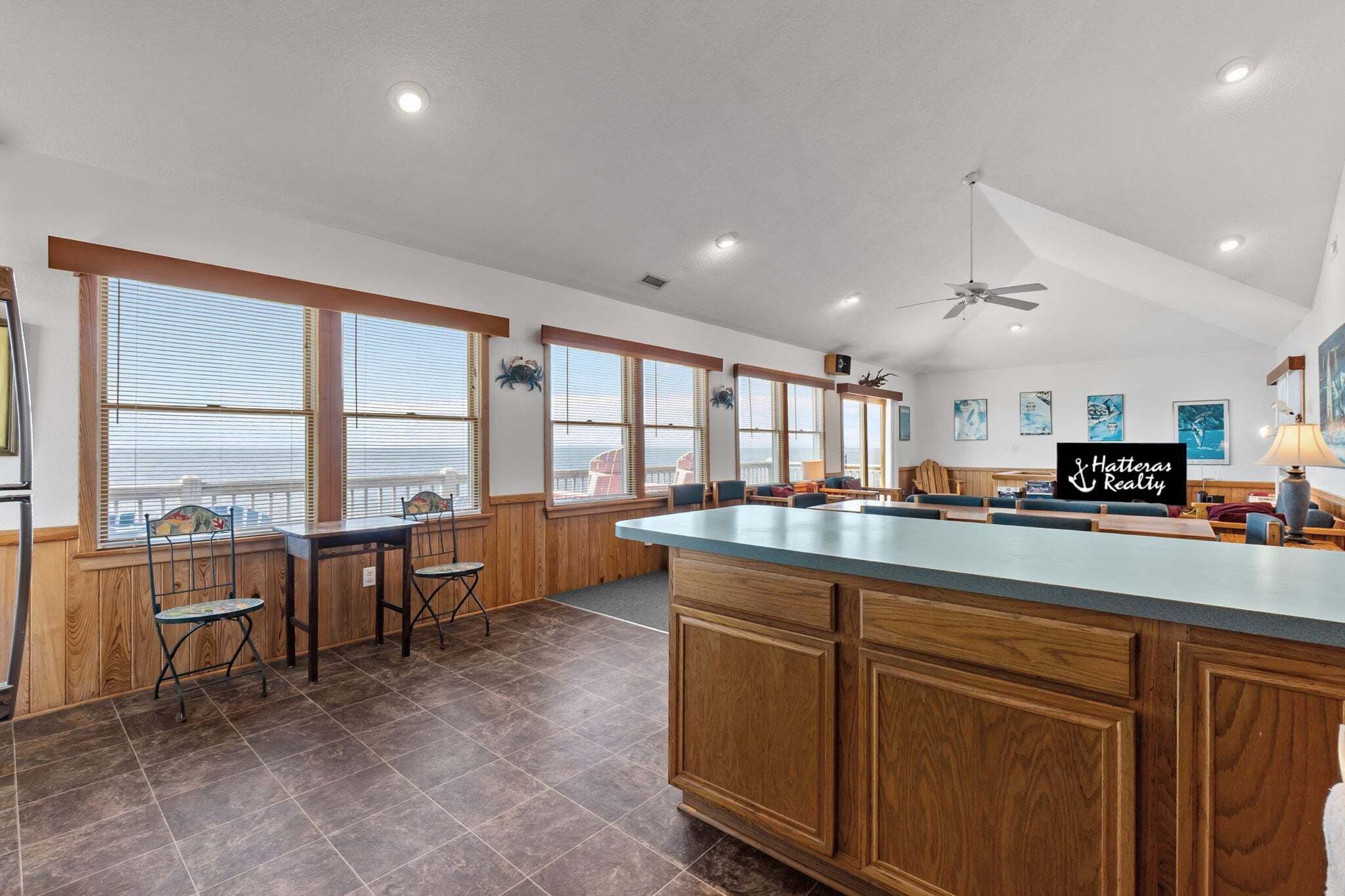 A spacious kitchen with a large island, wooden cabinetry, and a view of the city through large windows.