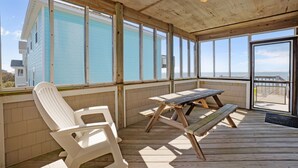 A covered outdoor area with a wooden deck, a table, and two chairs. - Waterfront home with private hot tub, windsurf launch, amazing view, pool access (Avon)