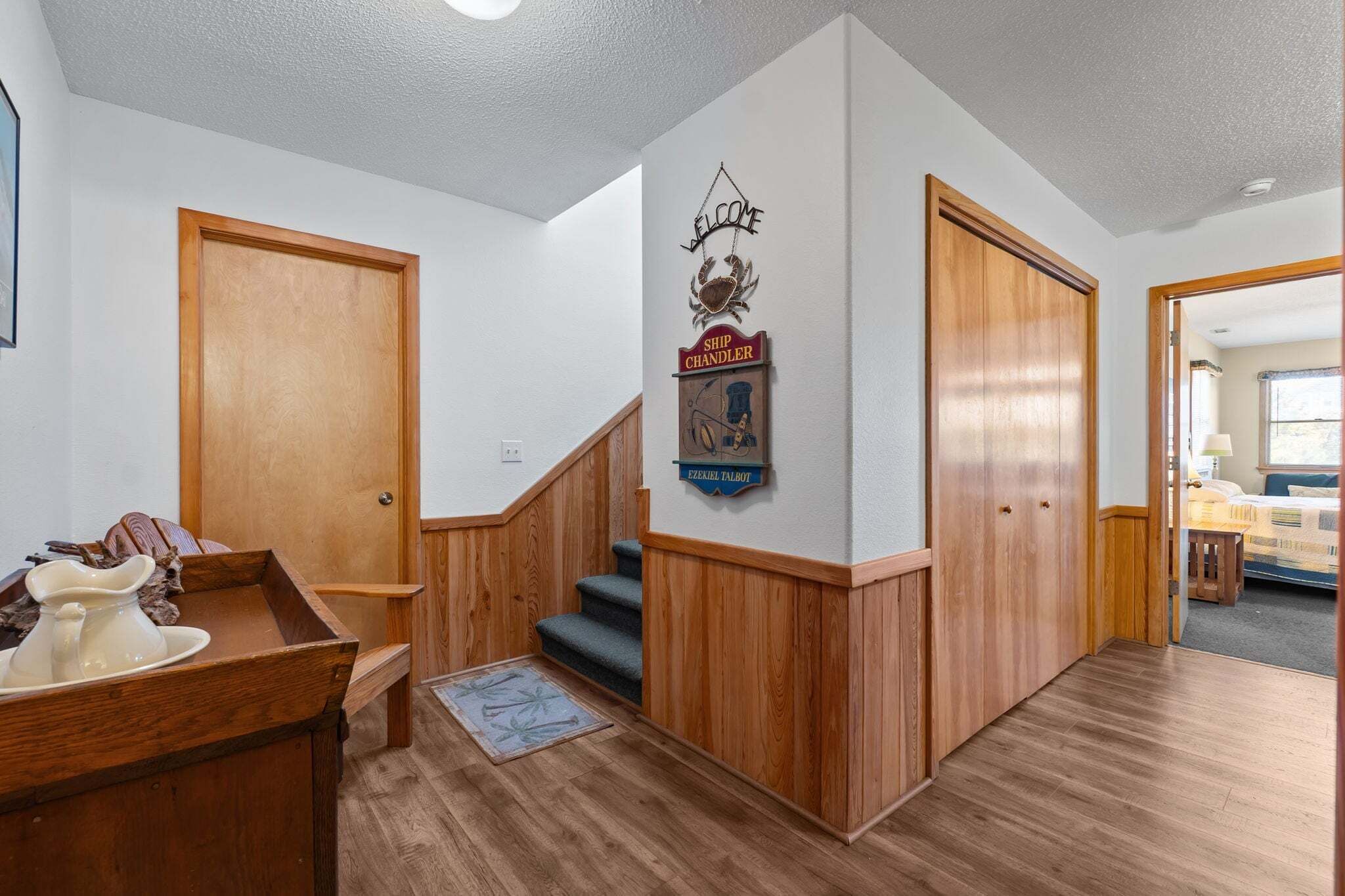 A hallway with wooden doors, a staircase, and a welcome sign.