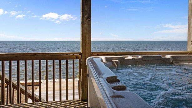A wooden deck with a hot tub overlooking a calm sea. - Waterfront home with private hot tub, windsurf launch, amazing view, pool access (Avon)