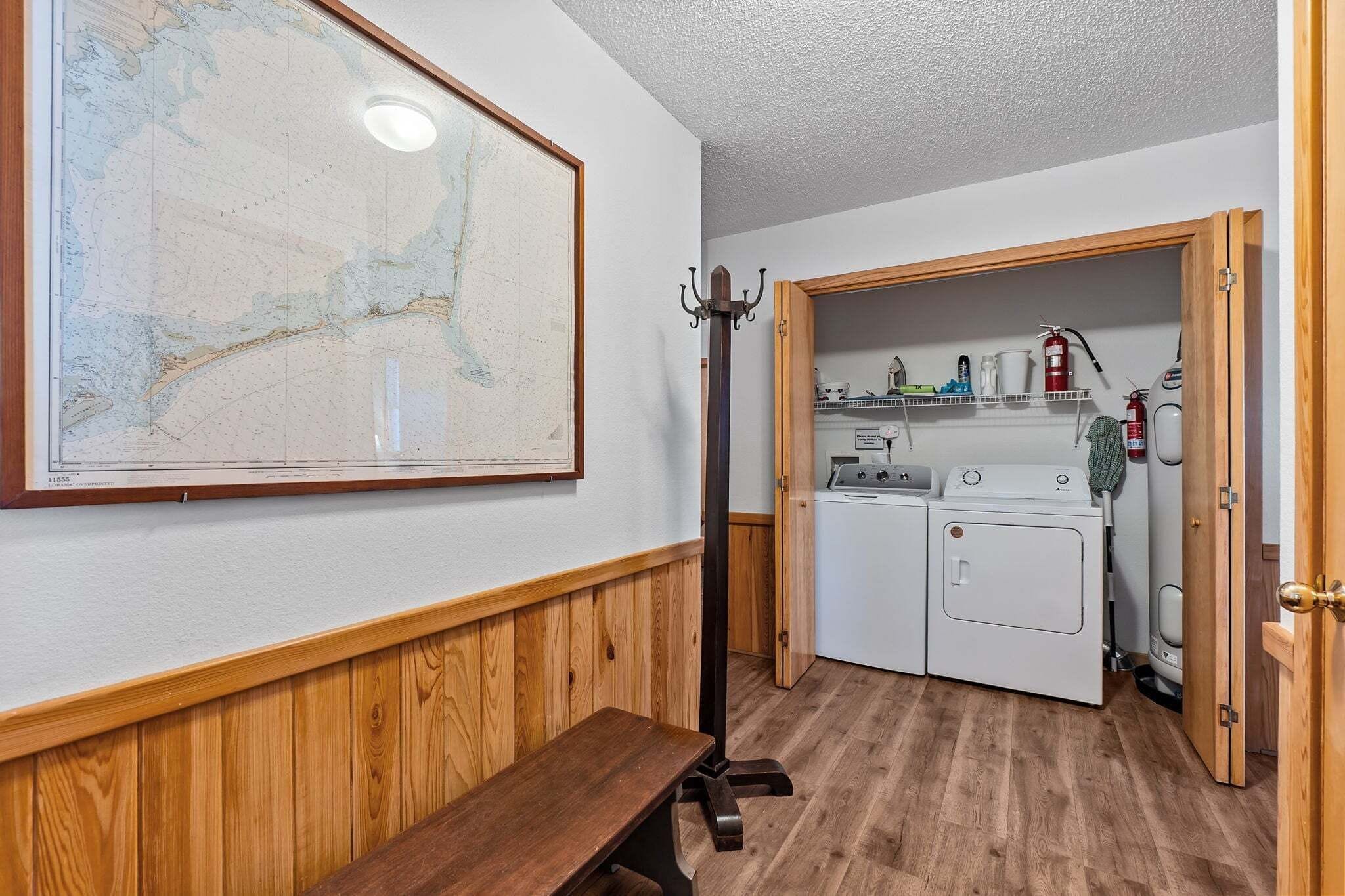 A room with a wooden bench, a map on the wall, a washing machine, and a fire extinguisher.