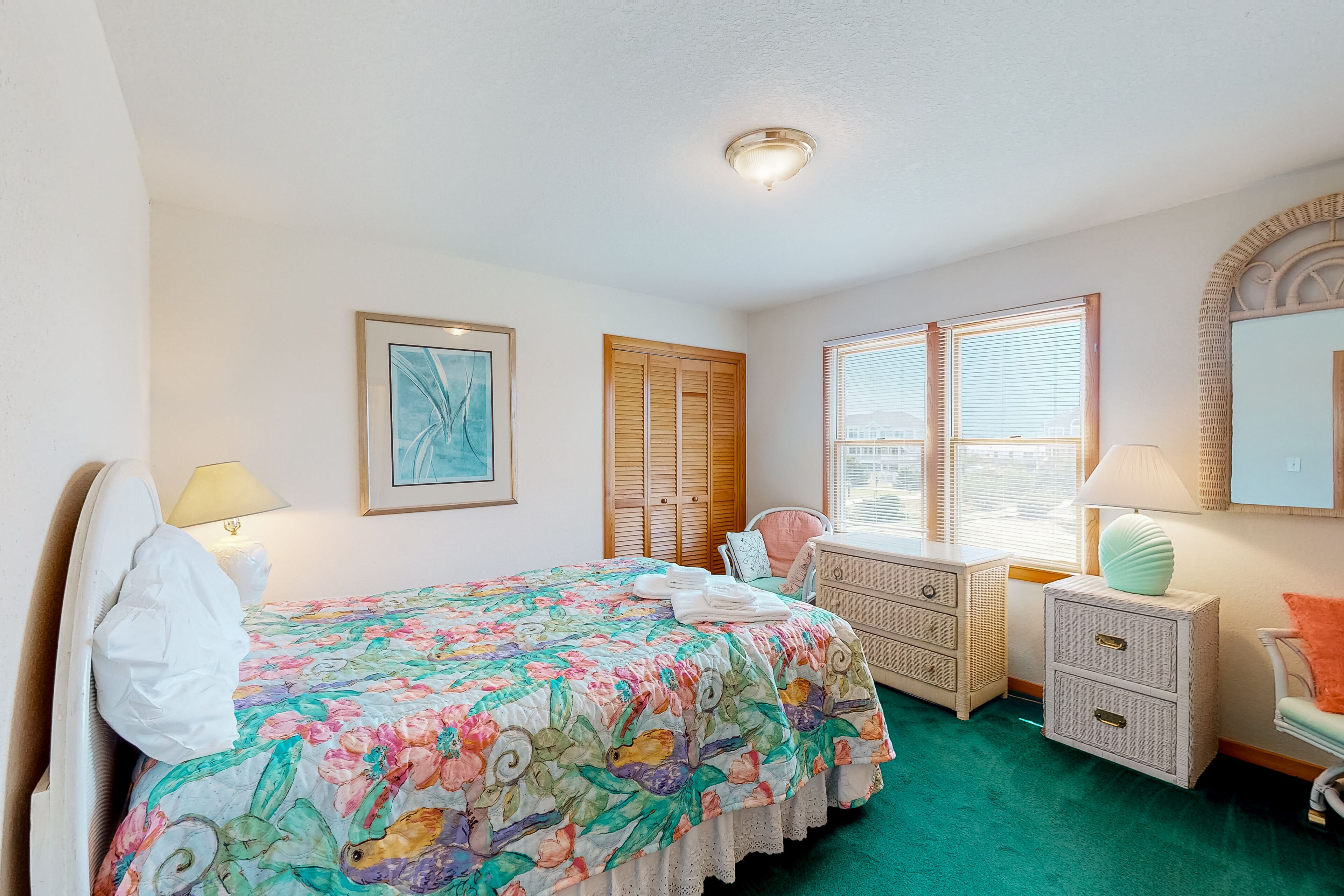 A bedroom with a bed, bedside tables, a dresser, a chair, and a window with blinds.