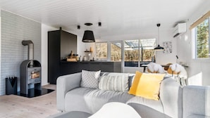 Ein modernes Wohnzimmer mit einem grauen Sofa, einem gelben Kissen und einem Kamin.