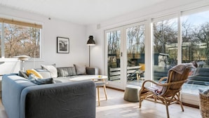 Ein modernes Wohnzimmer mit einem grauen Sofa, einem Korbstuhl und einem Esstisch.