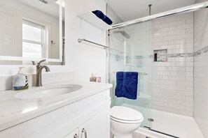 A modern bathroom with a white sink, a glass shower enclosure, and a white toilet. - Waterfront, Dog-Friendly Home w/ Sound View, Private Hot Tub, Dock & Shared Pool (Avon)