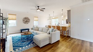A spacious living room with a sectional sofa, a coffee table, and a blue patterned rug. - Salty Escape: Newly Constructed Retreat (Oak Island)