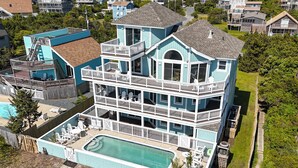 A multi-story house with a large front deck, a swimming pool, and a fenced backyard. - Multi-level dog-friendly oceanfront home with private pool & hot tub, rec room (Salvo)