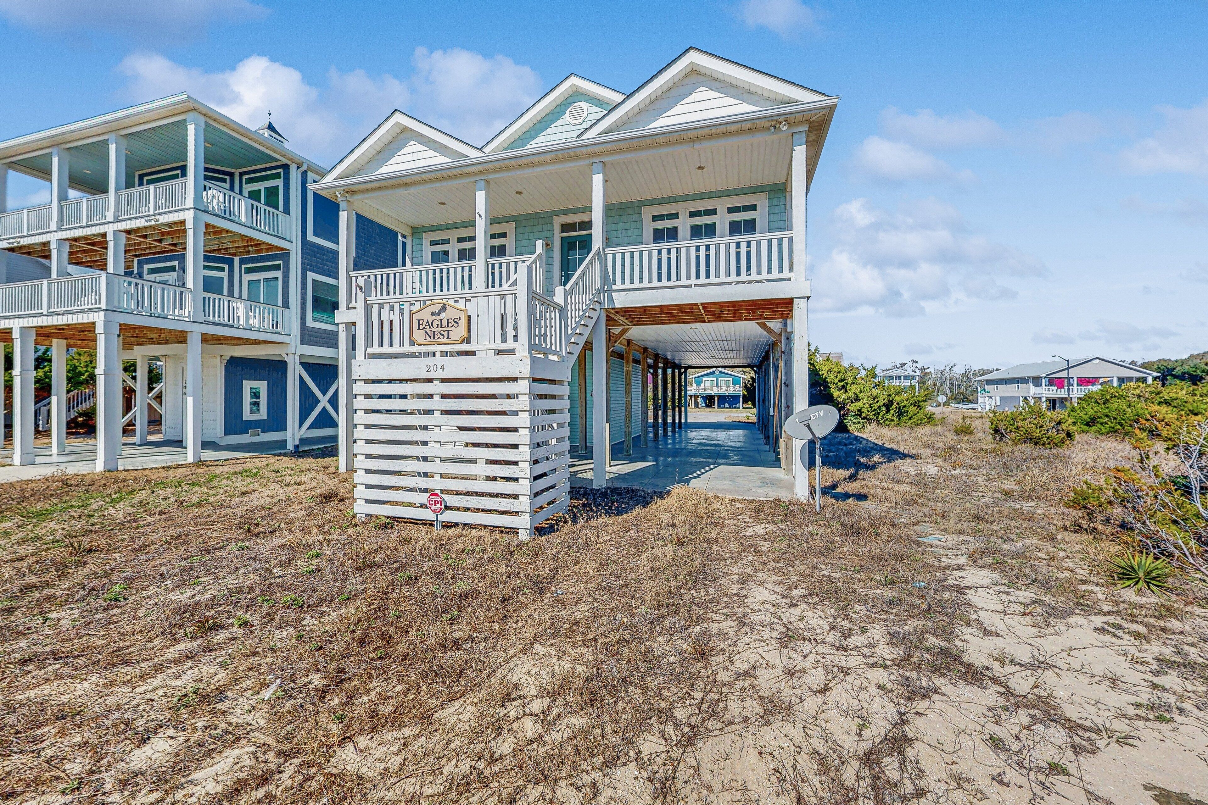 A beachfront property with a large house featuring multiple balconies and a covered porch.