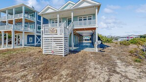 Een pand aan het strand met een groot huis, meerdere balkons en een overdekte veranda.