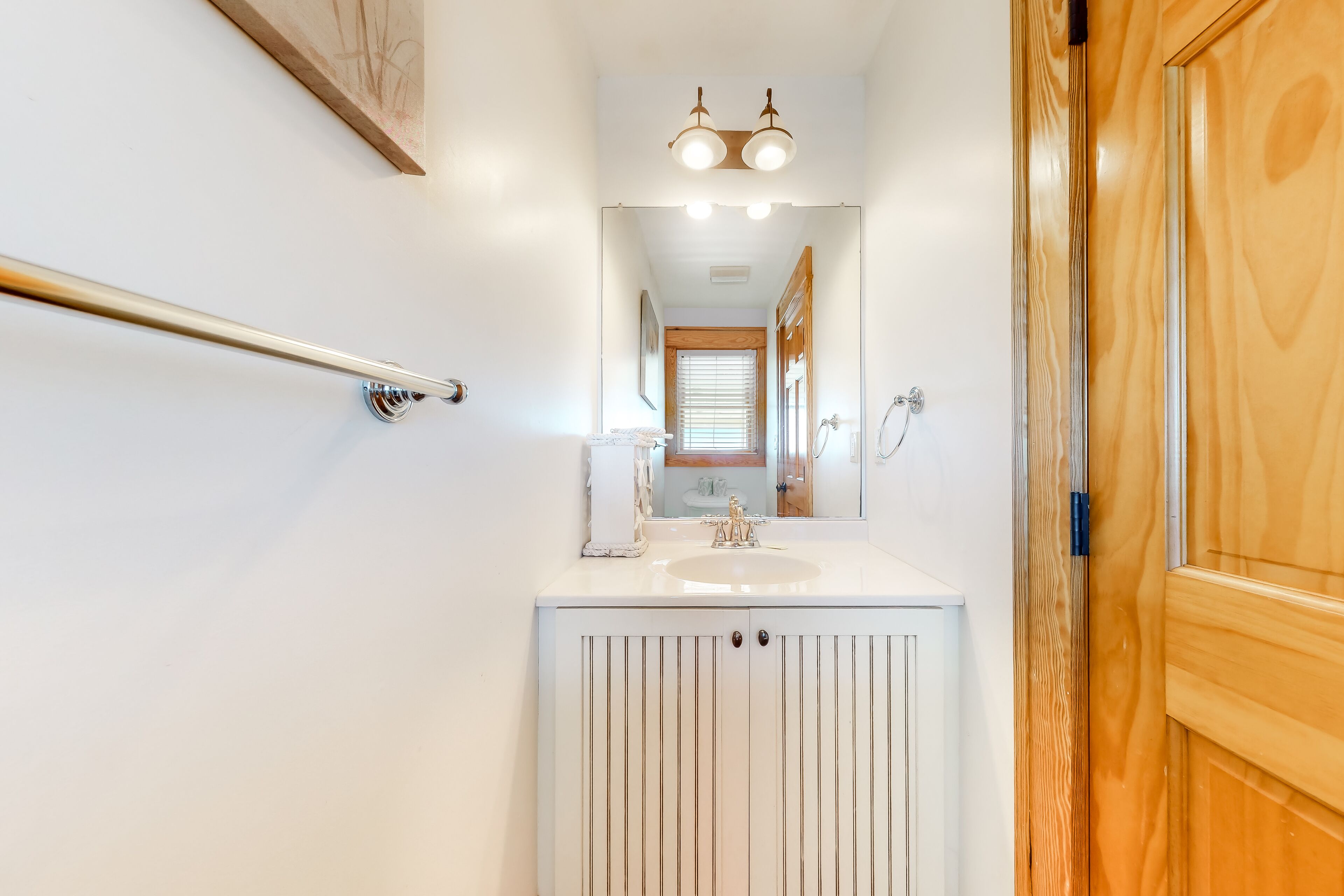 A bathroom with a white vanity, a mirror, and a wooden door.