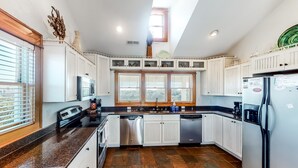 A modern kitchen with white cabinetry, a granite countertop, a dishwasher, and a refrigerator.