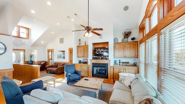 A spacious living room with a fireplace, wooden cabinets, and a ceiling fan.