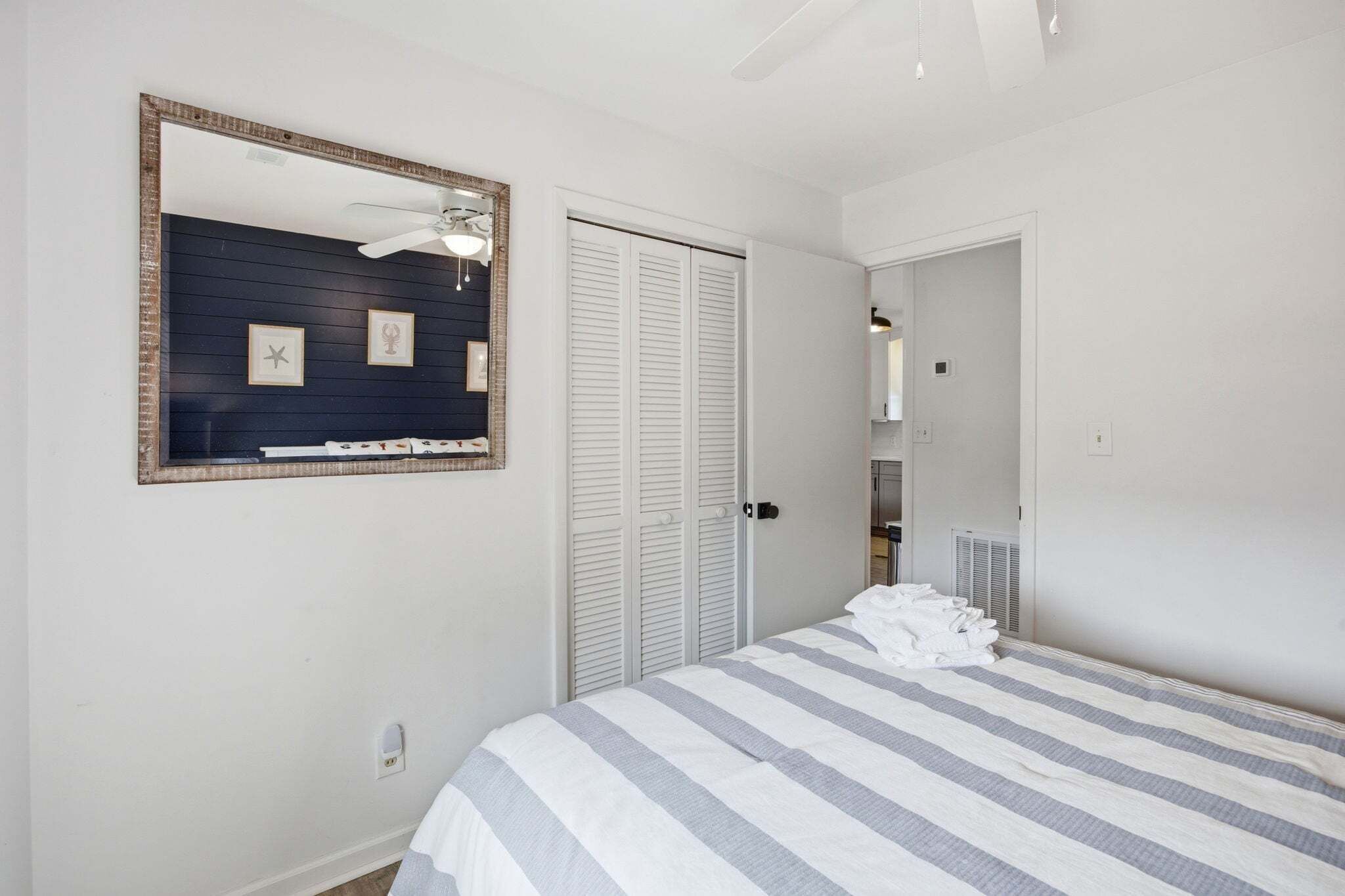 Une chambre à coucher avec un lit, un ventilateur de plafond, une armoire et un miroir.