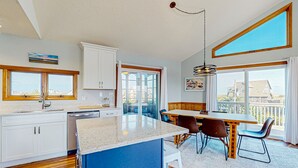 Una cocina moderna con una isla central, suelo de madera y amplios ventanales que ofrecen vistas de la ciudad.