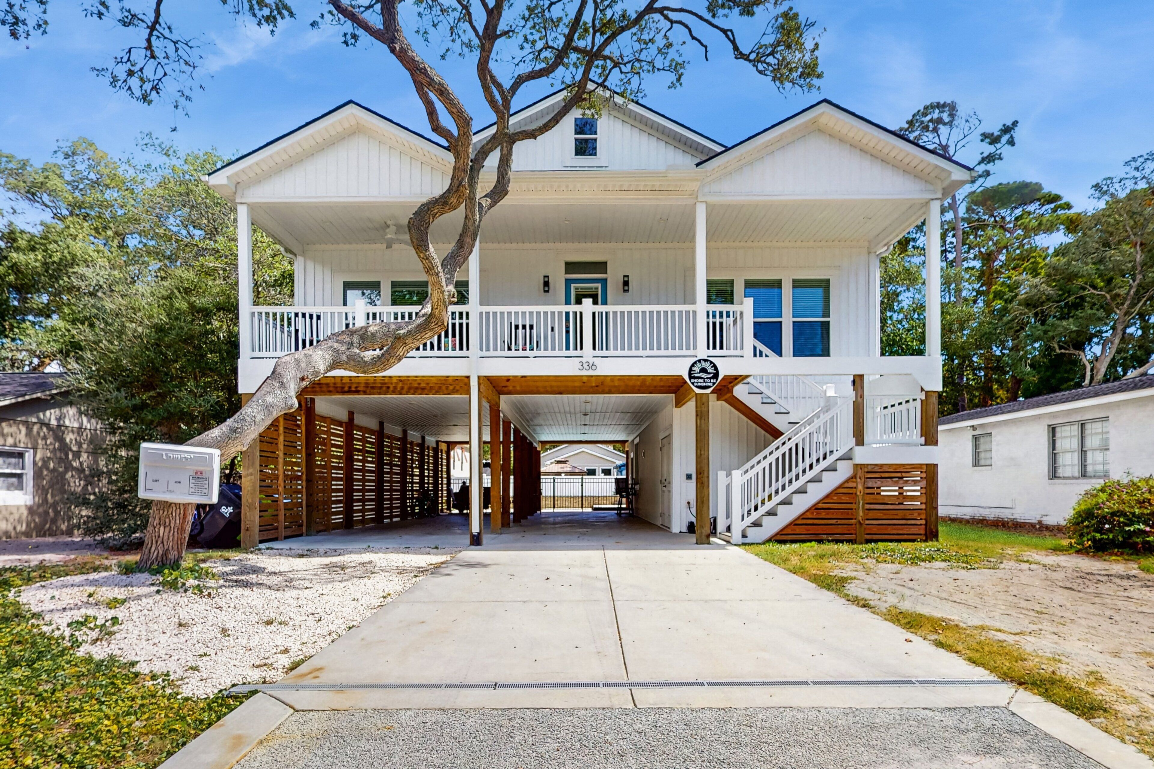 A two-story white house with a covered porch and a staircase leading to the second floor.