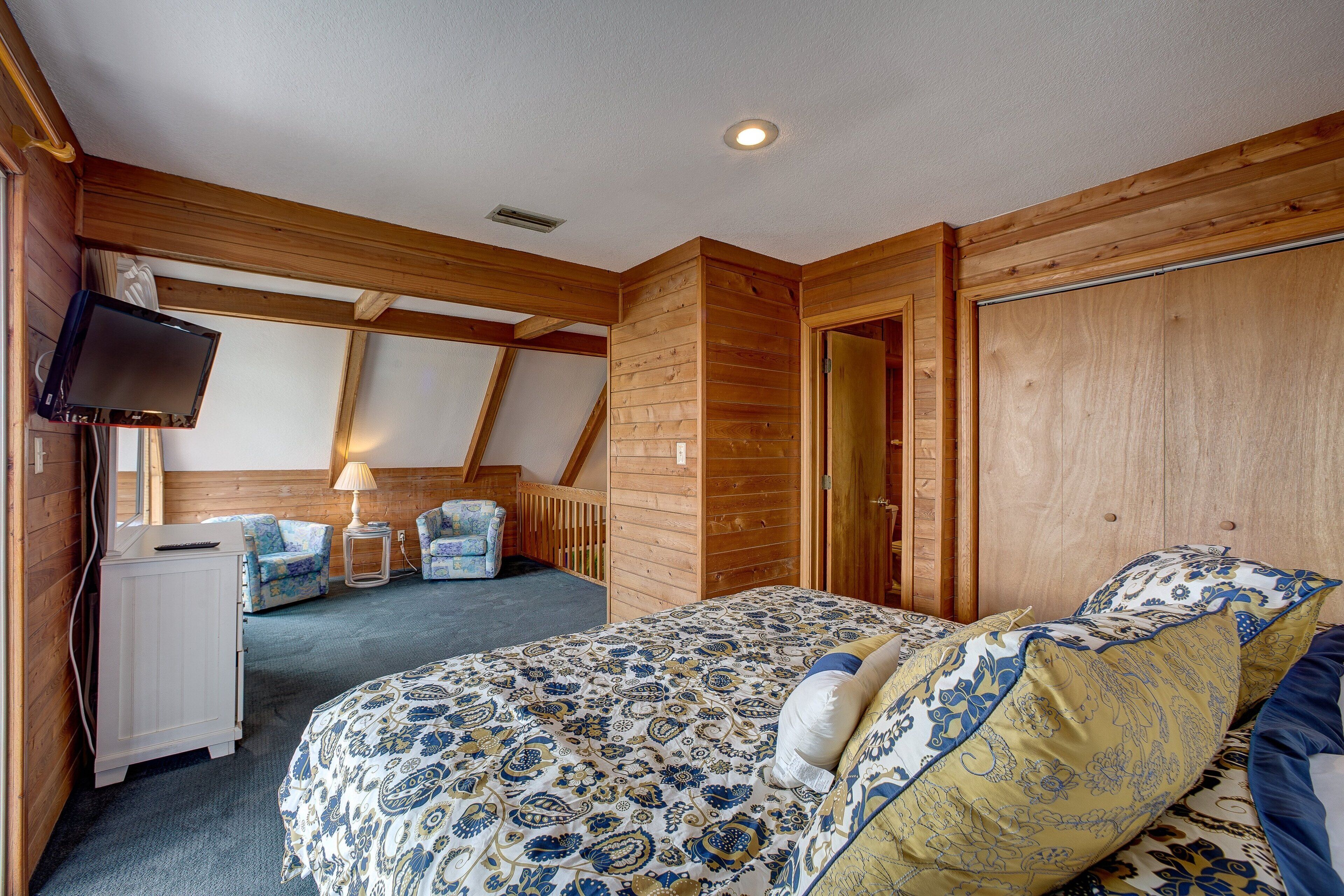 A bedroom with a bed, a TV, a desk, and a chair.