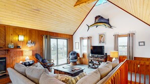 Una sala acogedora con un sofá grande, un televisor y techo de madera.