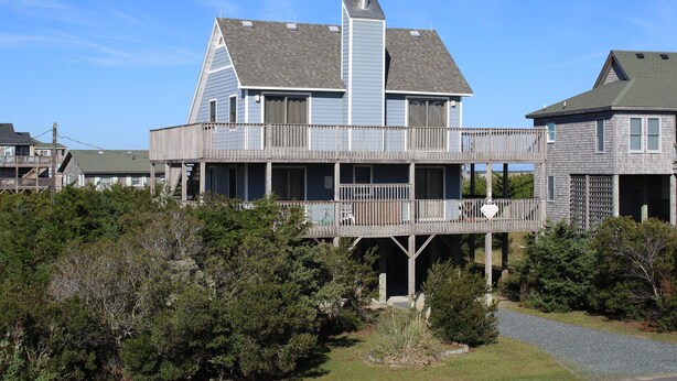 Una casa de dos pisos con balcón y terraza cubierta.