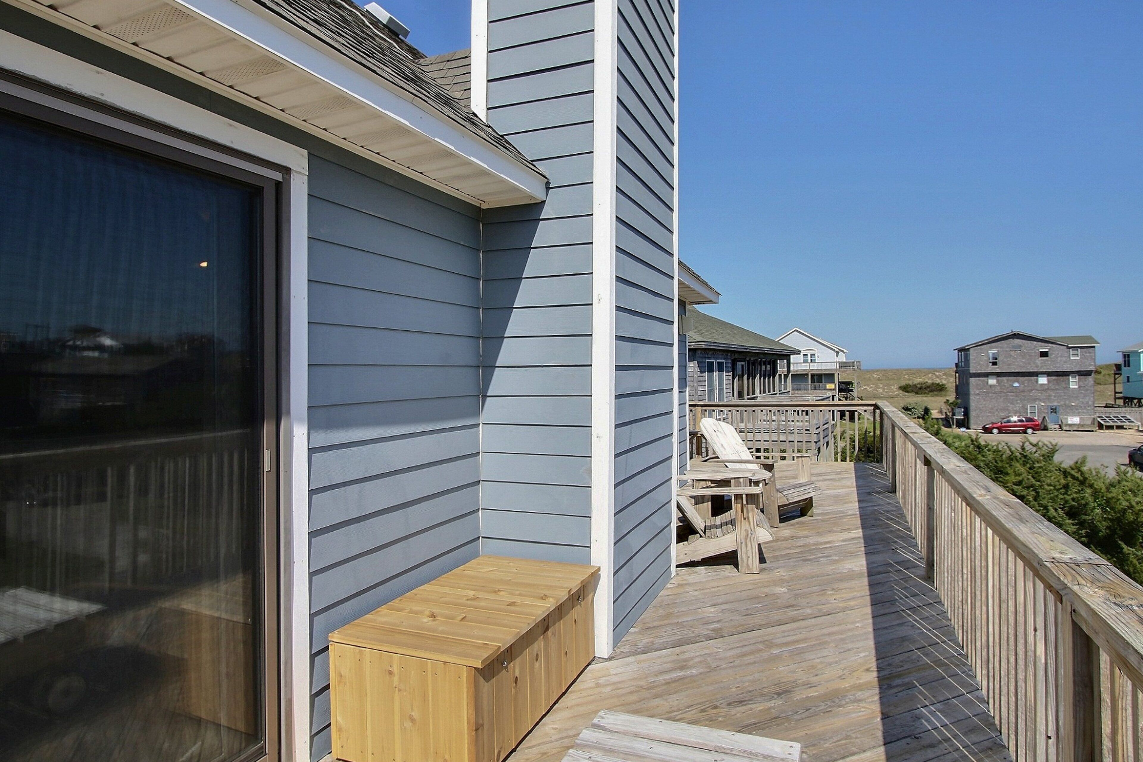 Une terrasse en bois avec un banc, un espace abrité et une vue sur les maisons voisines.