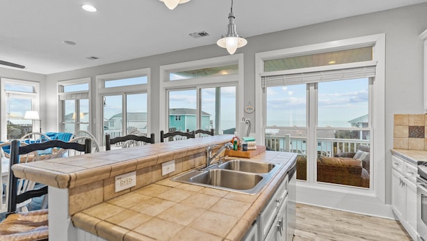 A modern kitchen with a large island, ample natural light, and a view of the ocean. - The Doobler: Ocean Views, Near Beach and Golf (Ocean Isle Beach)