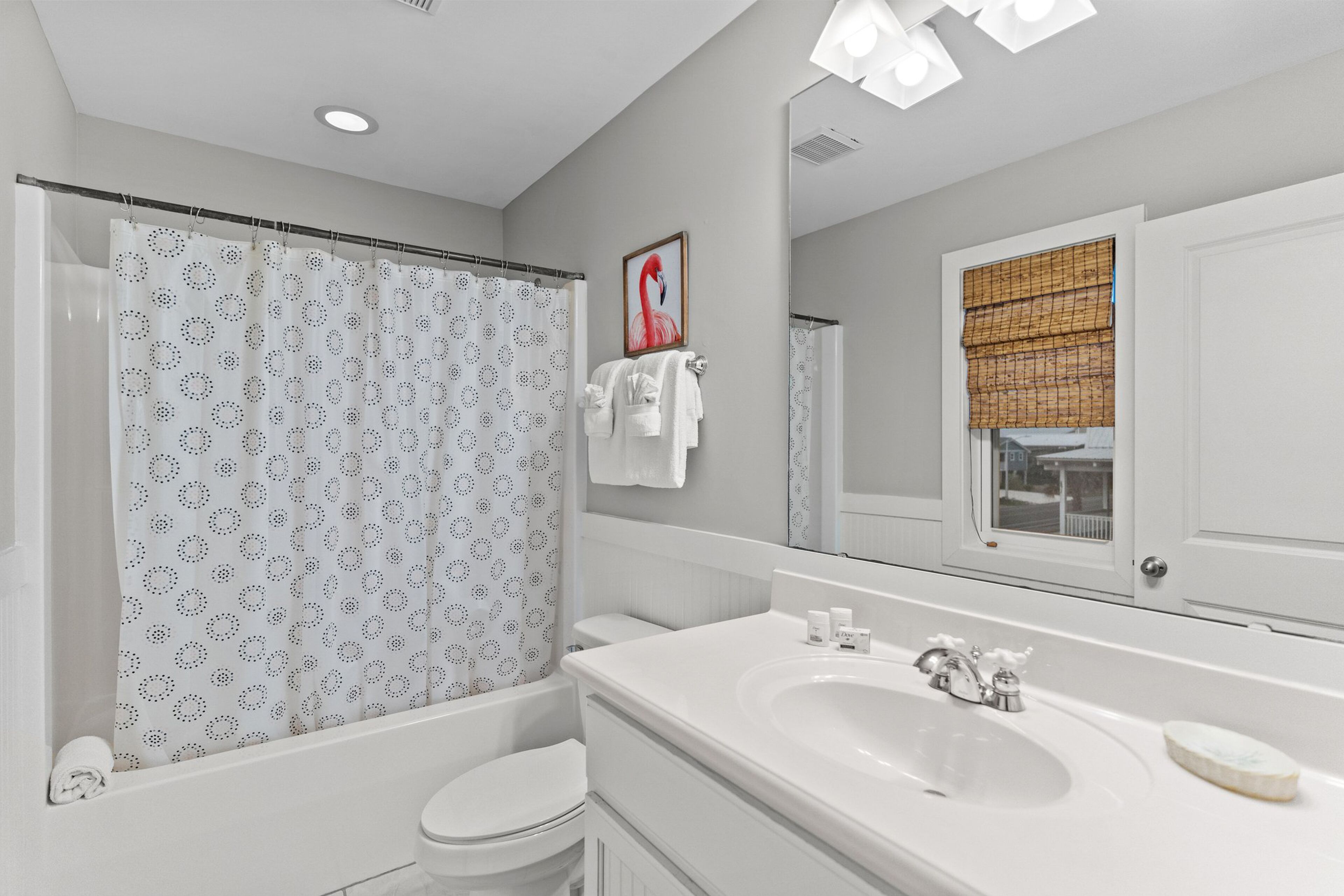 A modern bathroom with a shower curtain, toilet, sink, and a large mirror.