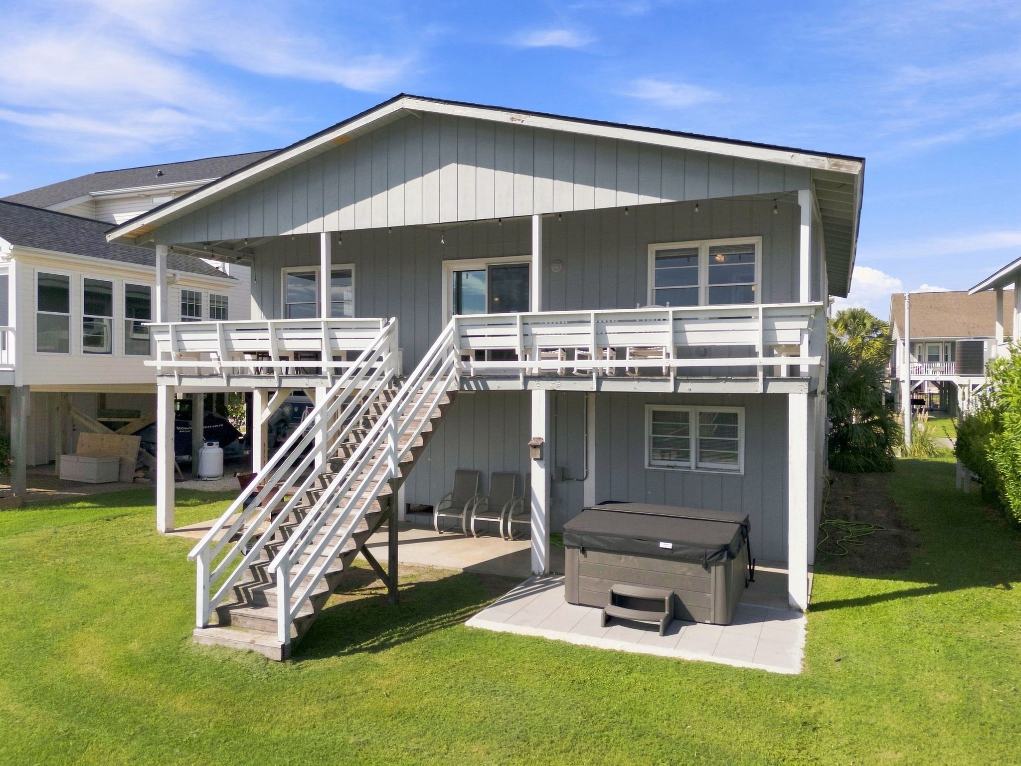 Une maison à deux étages dotée d’un patio couvert, d’un escalier et d’un barbecue.