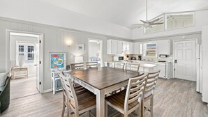 A spacious kitchen with white cabinetry, a central island, and a dining area with wooden chairs.