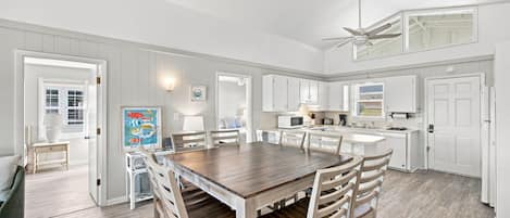 A spacious kitchen with white cabinetry, a central island, and a dining area with wooden chairs.
