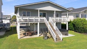 A two-story house with a covered patio, outdoor seating, and a staircase leading to the upper level.