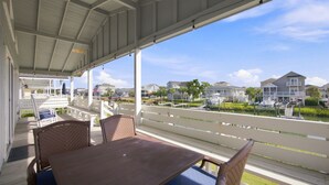 A covered outdoor seating area with a view of a marina and houses.
