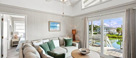A spacious living room with a large sofa, a coffee table, and a view of a pool and outdoor area.