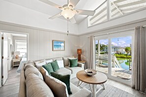 A spacious living room with a large sofa, a coffee table, and a view of a pool and outdoor area. - Toes in the Water: Canal, Dog Friendly, Hot tub (Ocean Isle Beach)