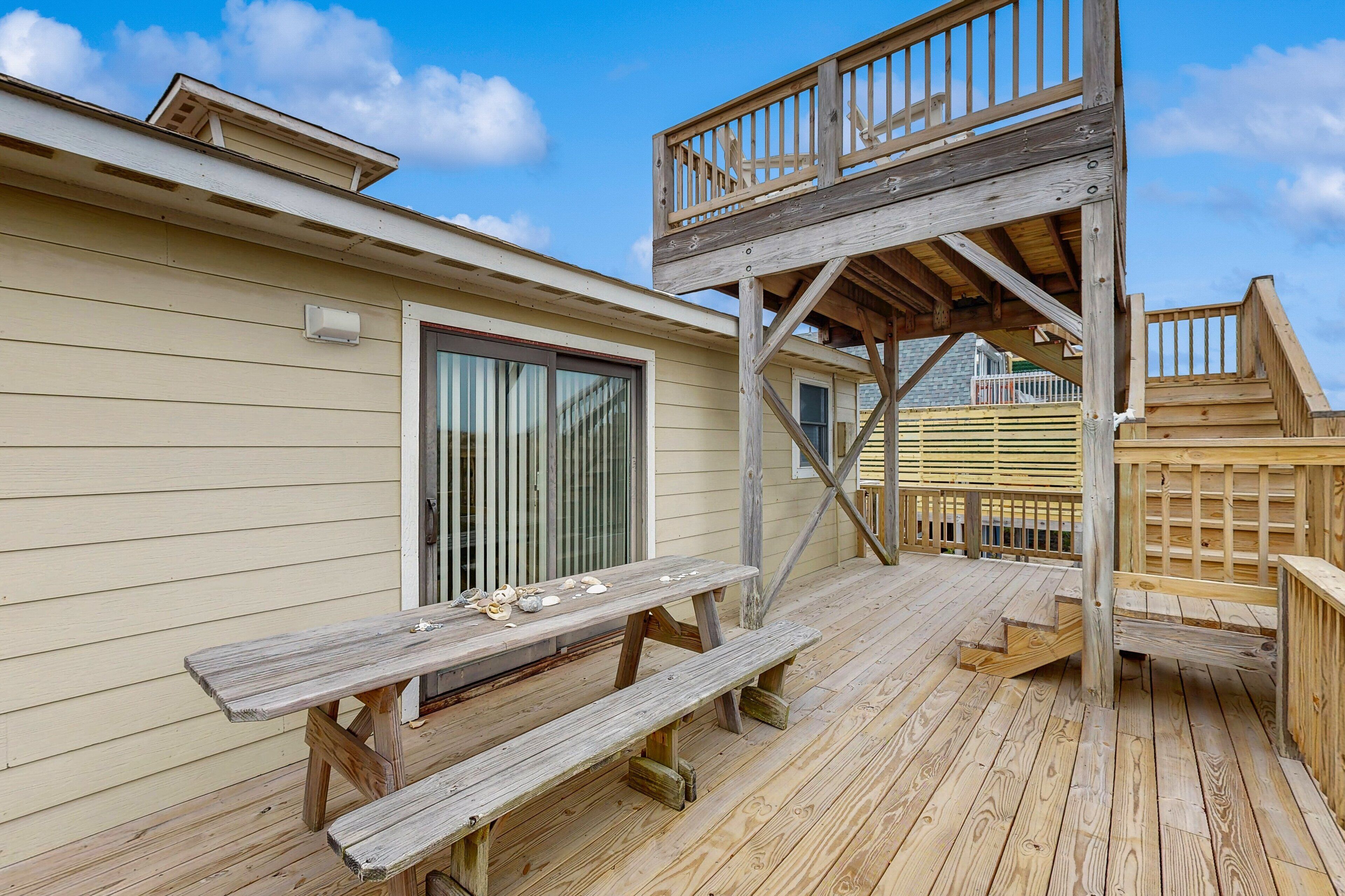 A wooden deck with a picnic table and a wooden staircase leading to a deck area.