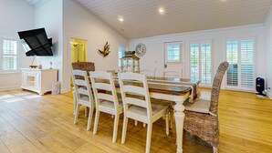 A dining area with a wooden table, white chairs, and a wicker chair.