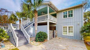 A two-story house with a balcony, a staircase, and a palm tree.