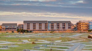 Un complesso residenziale con diversi edifici, un cortile centrale con tavoli da picnic e cielo sereno.