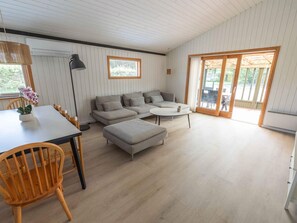 A modern living room with a sofa, ottoman, and dining table. - 4 Star Holiday Home in Vaeggerlose (Vaeggerlose)