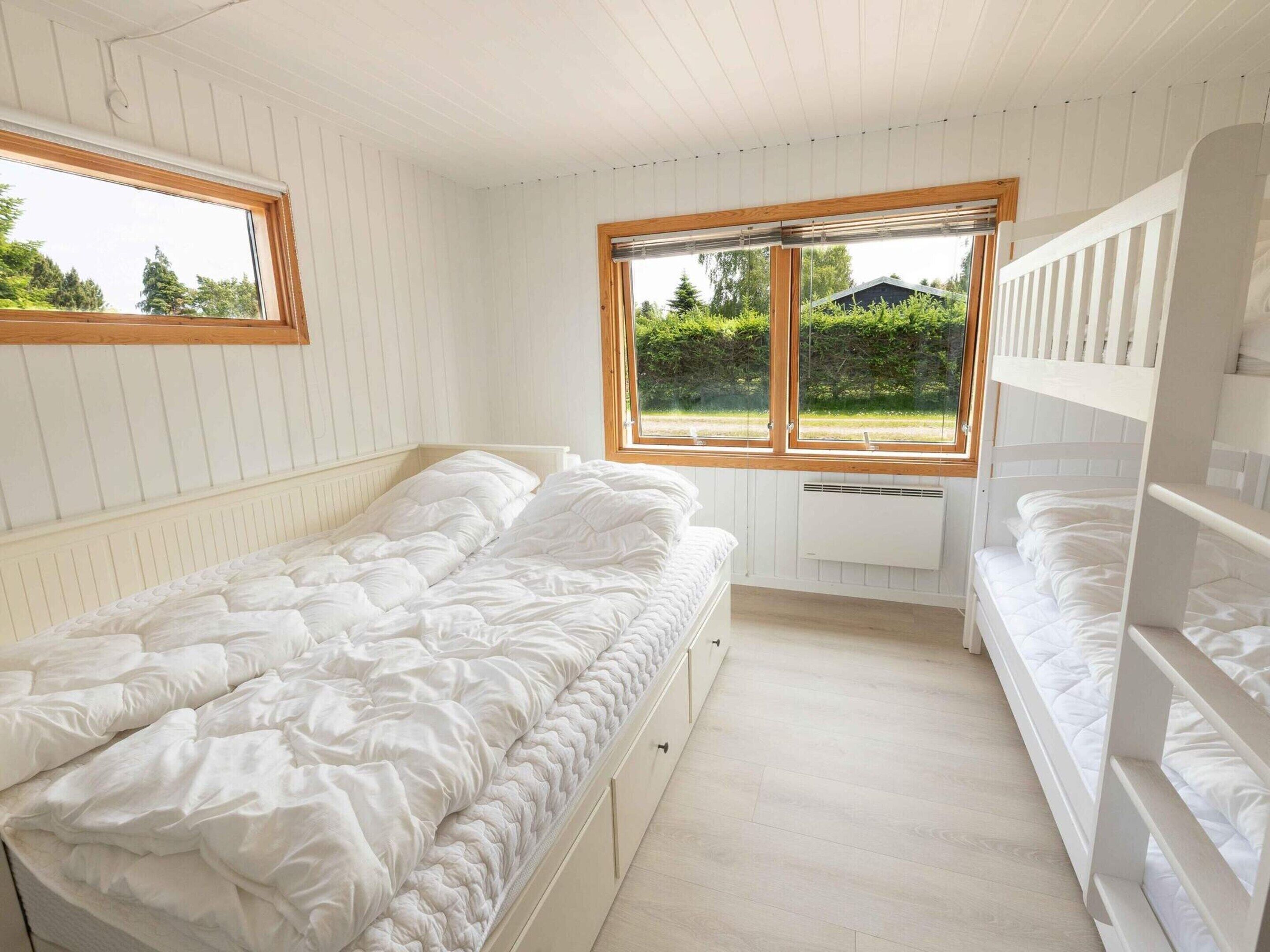 A small, single-bedroom room with a bunk bed, a window with a view of greenery, and a radiator under the window.