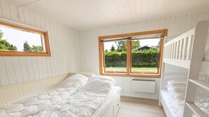 A small, single-bedroom room with a bunk bed, a window with a view of greenery, and a radiator under the window. - 4 Star Holiday Home in Vaeggerlose (Vaeggerlose)