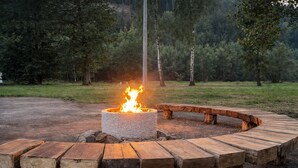 Un pozo de fuego circular con llamas, rodeado por un banco de madera.