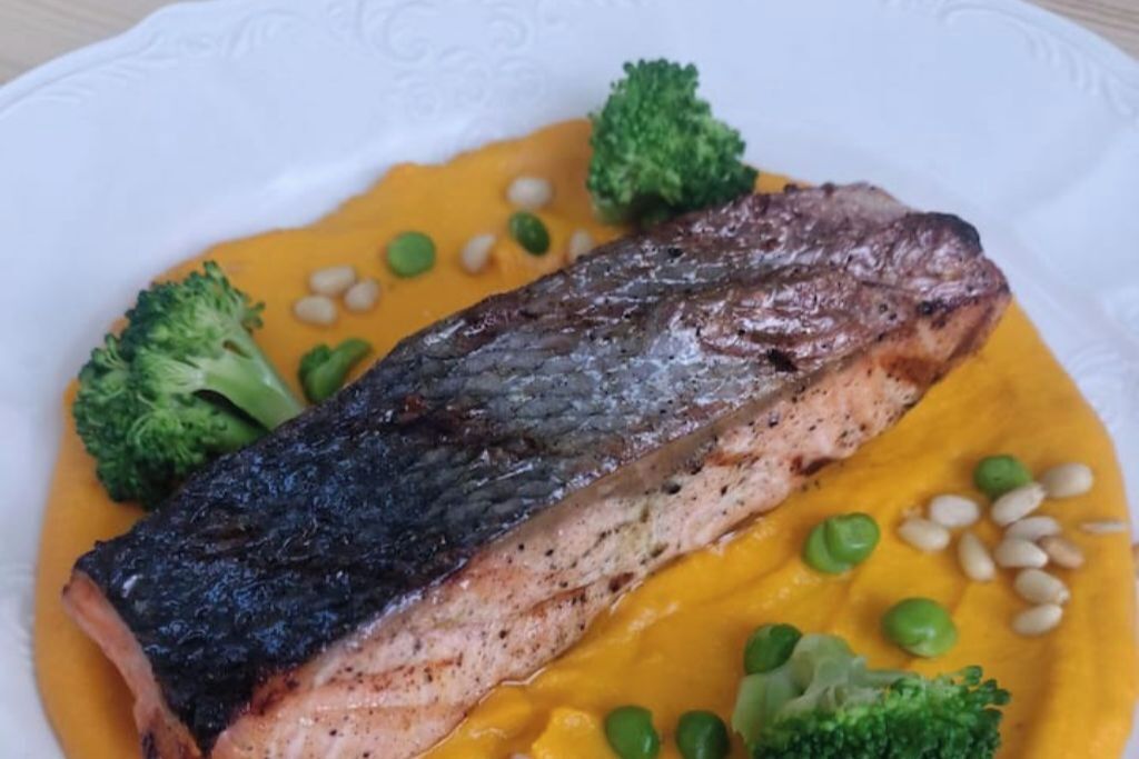 Ein Teller mit gegrilltem Fisch, Brokkoli und einer gelben Soße.