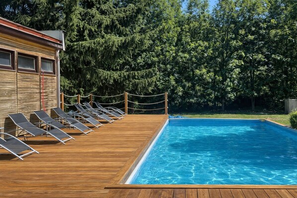 A swimming pool with a wooden deck and lounge chairs. - Carlsbad Wellness & Camping Resort (Březová)