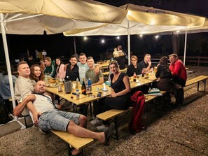 A group of people seated at a long wooden table under a large canopy tent. - Carlsbad Wellness & Camping Resort (Březová)